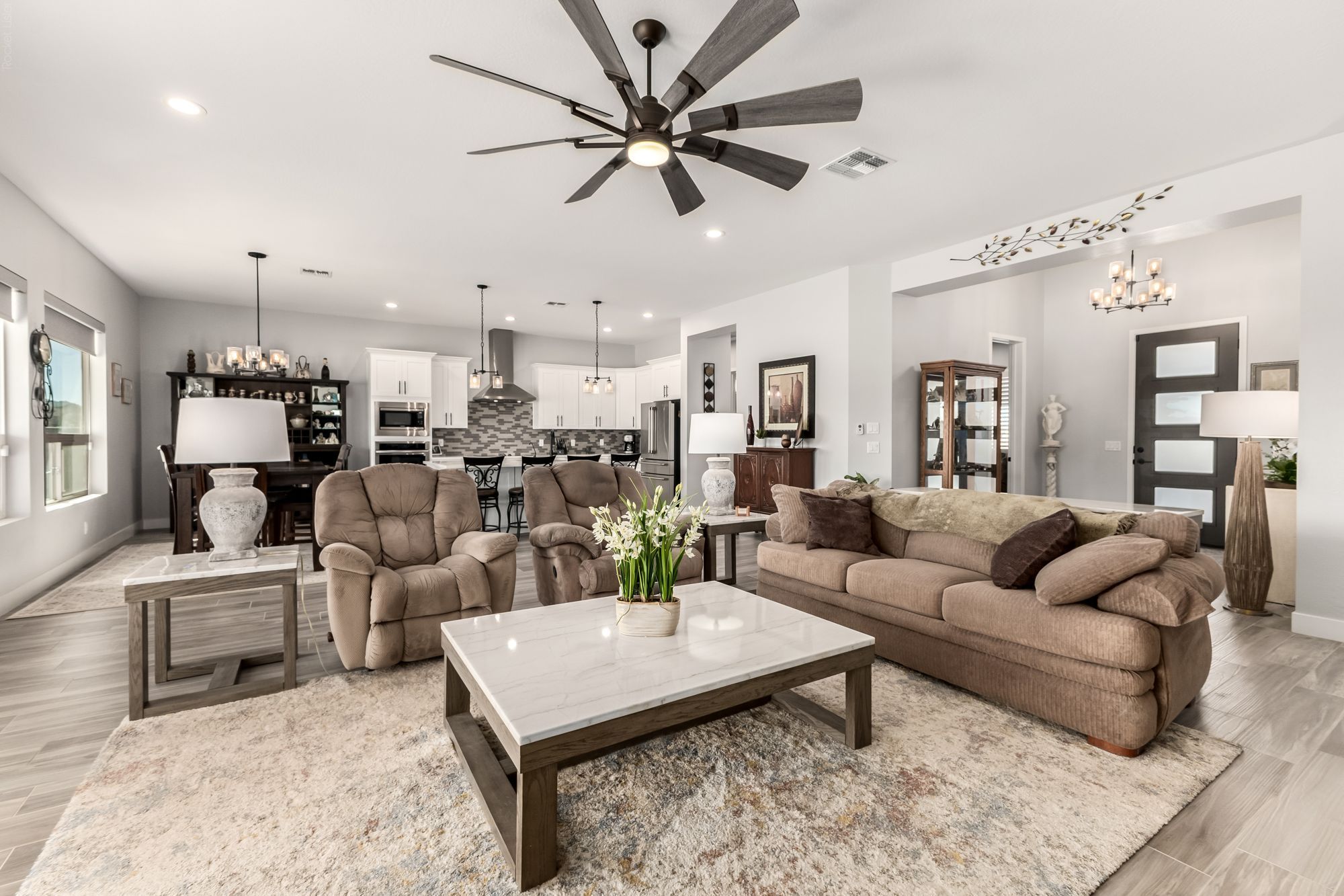 Open great room with a ceiling fan and large windows