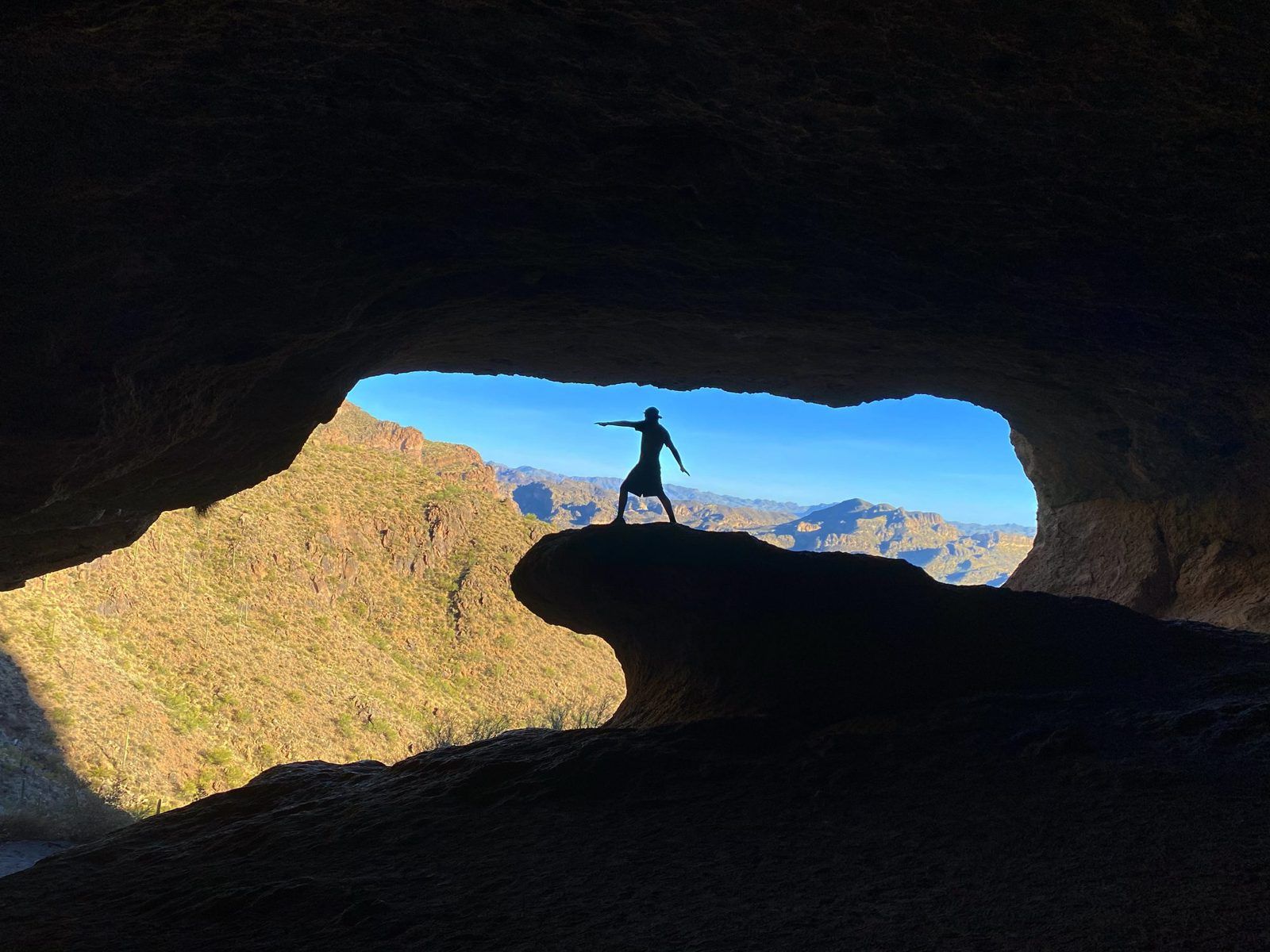 Stephen standing in a cave opening overlooking the desert